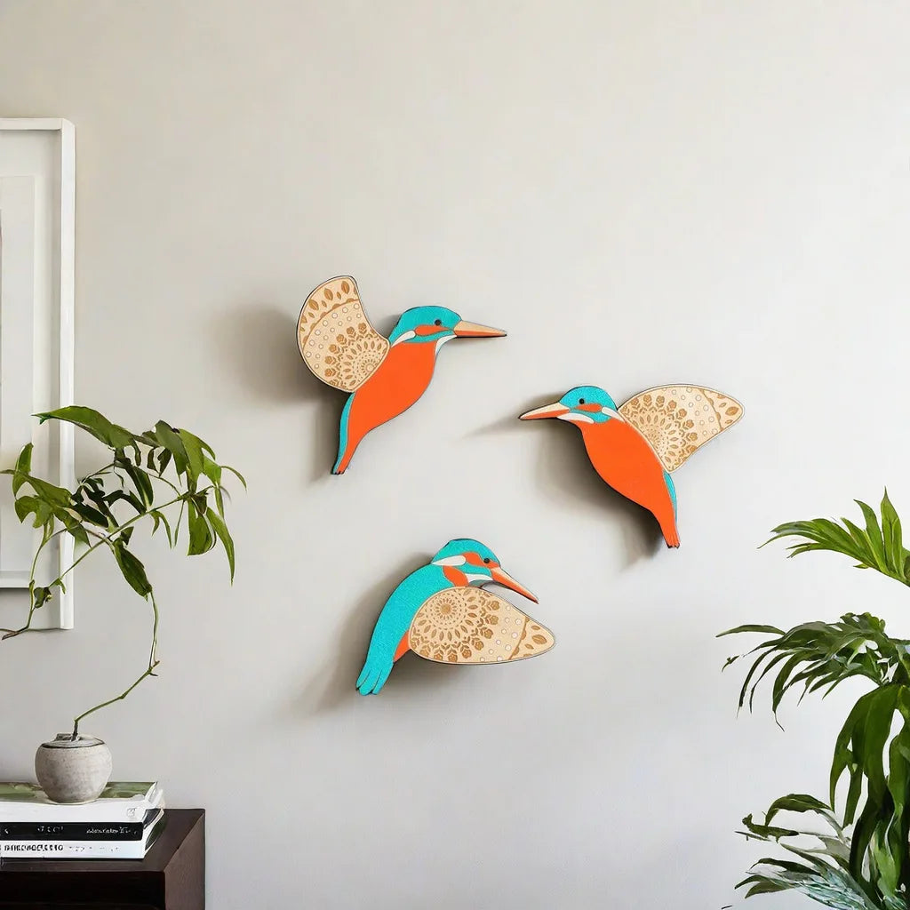 A set of three vintage wooden bird wall decorations in orange and blue hues mounted on a light gray wall.