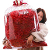 Une femme tient un sac en plastique transparent rempli de pétales de roses rouges artificielles pour la décoration.