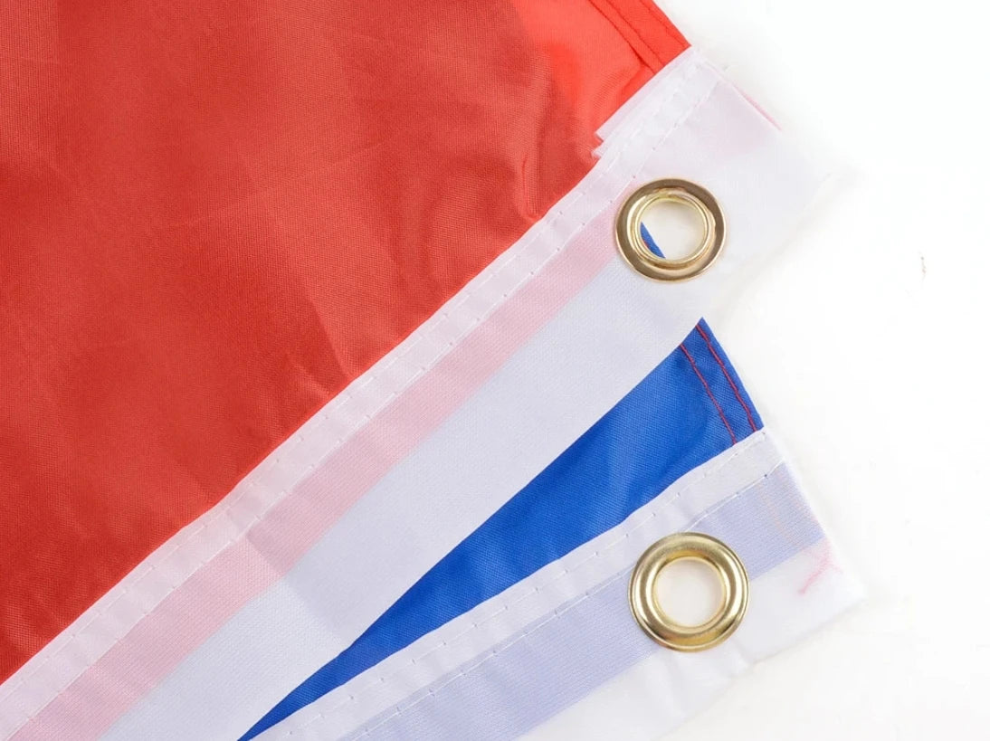 A close-up of a red and white flag banner with blue stripes, featuring grommets for hanging.