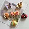 A collection of cute insect resin fridge magnets including a purple butterfly, bee, snail, ladybug, and dragonfly.
