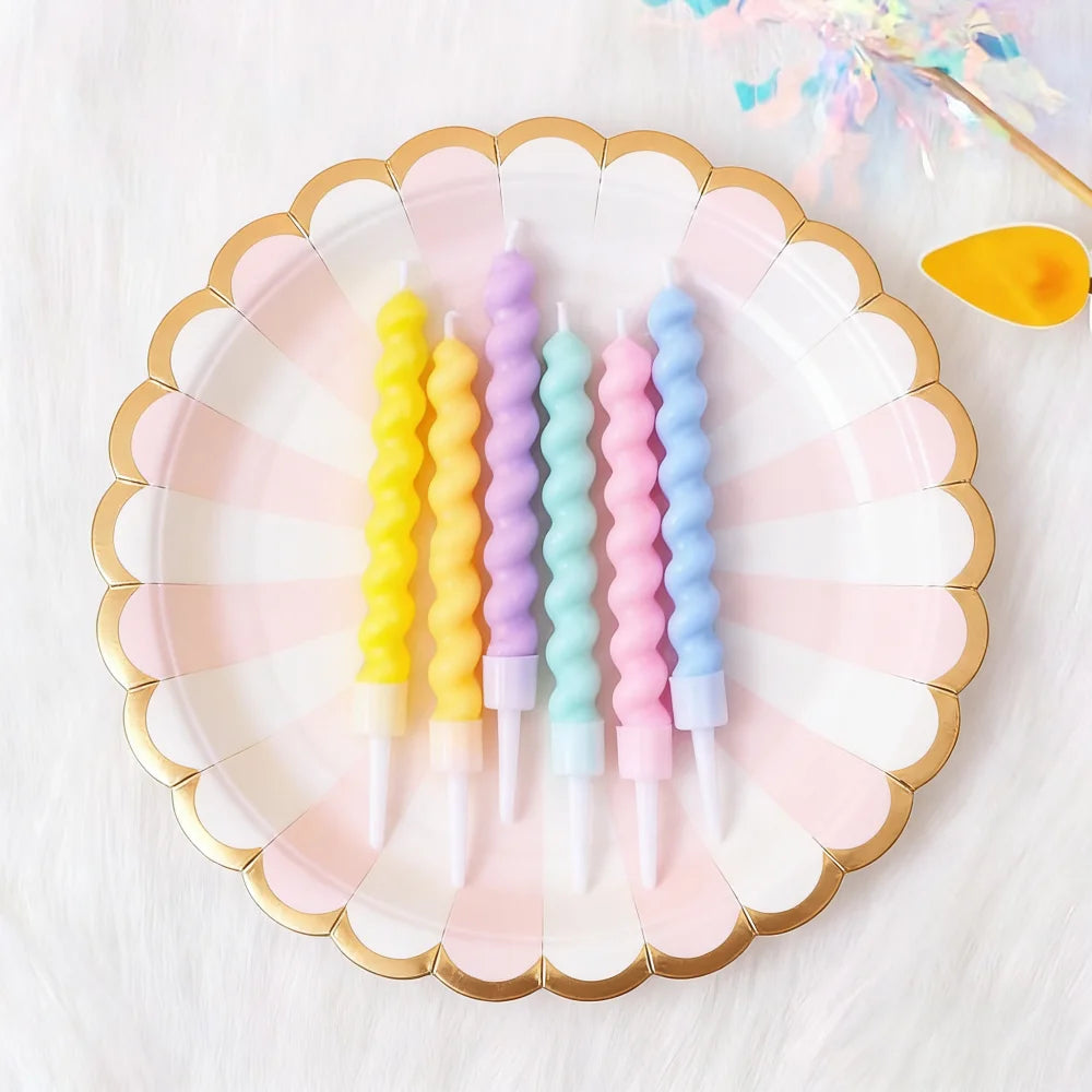 A plate holds several colorful spiral birthday cake candles with star toppers on a white fluffy surface.