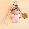 Un ours en peluche moelleux portant une salopette rose et des lunettes de pilote attachées à une clé en cuir.