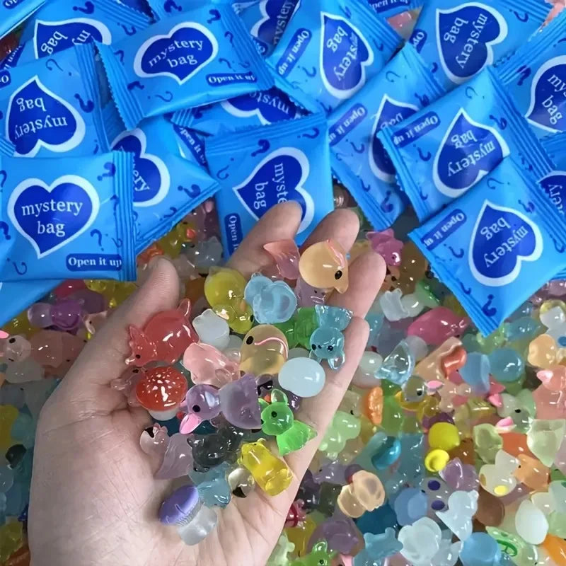 A hand holds a collection of glow in the dark resin decor pieces for fairy gardens alongside packaged mystery bags.