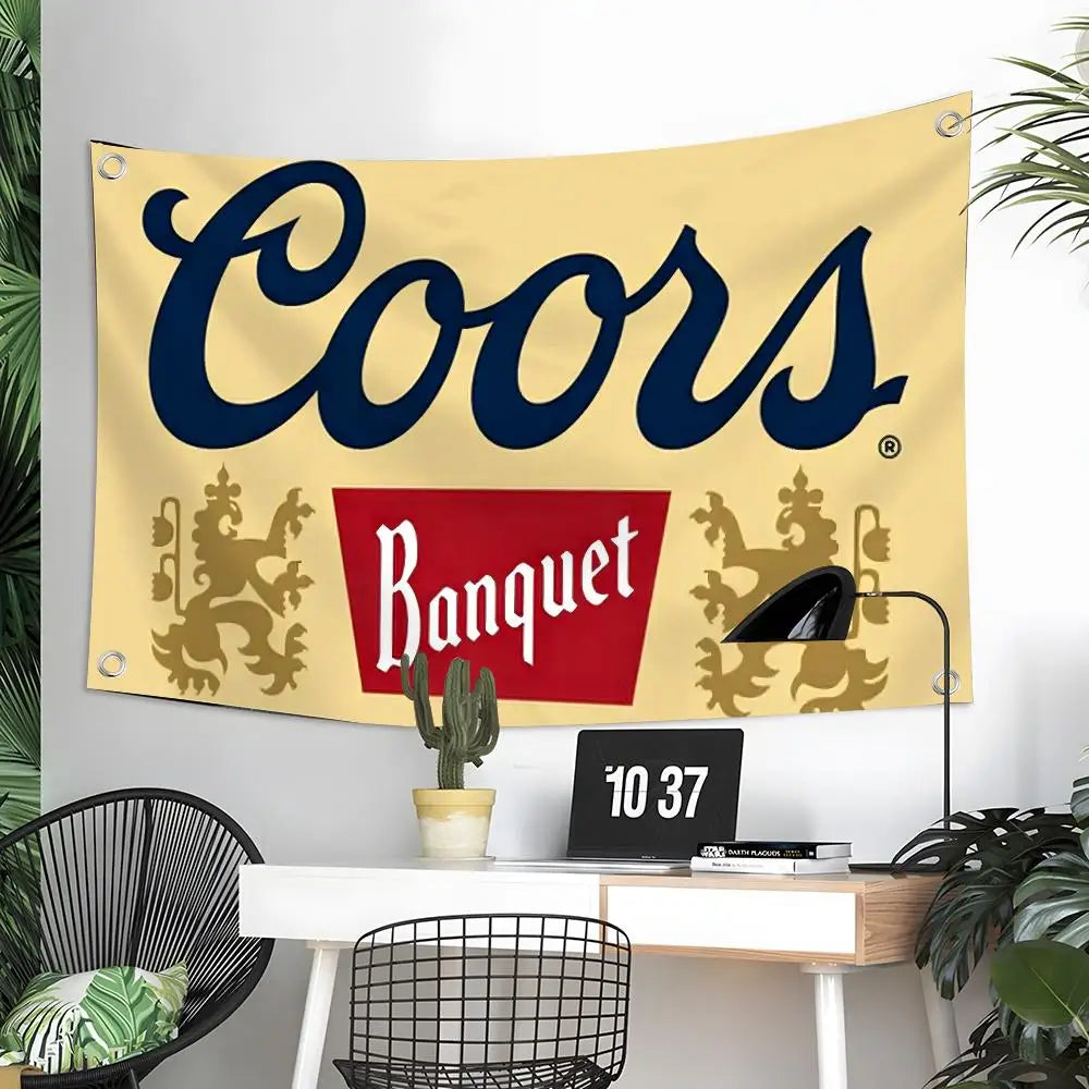 Beige Banner mit der Aufschrift Coors in dunkelblauer Schrift und dekorativem goldenem Laub, an einer weißen Wand