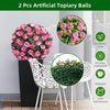 Two artificial topiary balls of pink roses displayed on a table with white chairs.