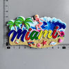 A colorful magnet featuring a woman in a tropical setting and the word Miami