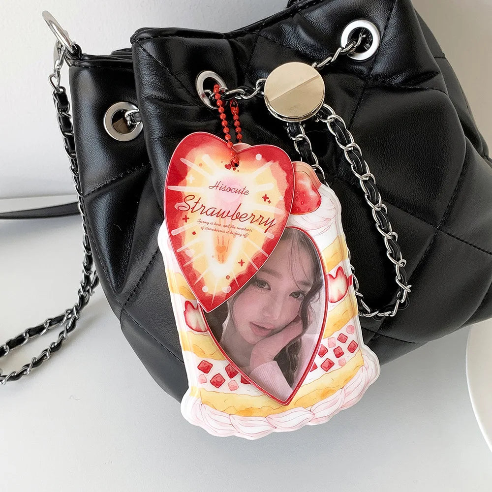 A black faux leather bag with a strawberry-themed keychain featuring a heart-shaped card holder.