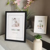 A black photo frame displaying the word WELCOME, resting on a light surface next to a potted pink orchid.