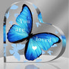 A vibrant blue butterfly with black wings is featured on a heart-shaped acrylic table decor, surrounded by inspirational text