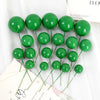 A set of twenty bright green ball cake toppers arranged on white paper.
