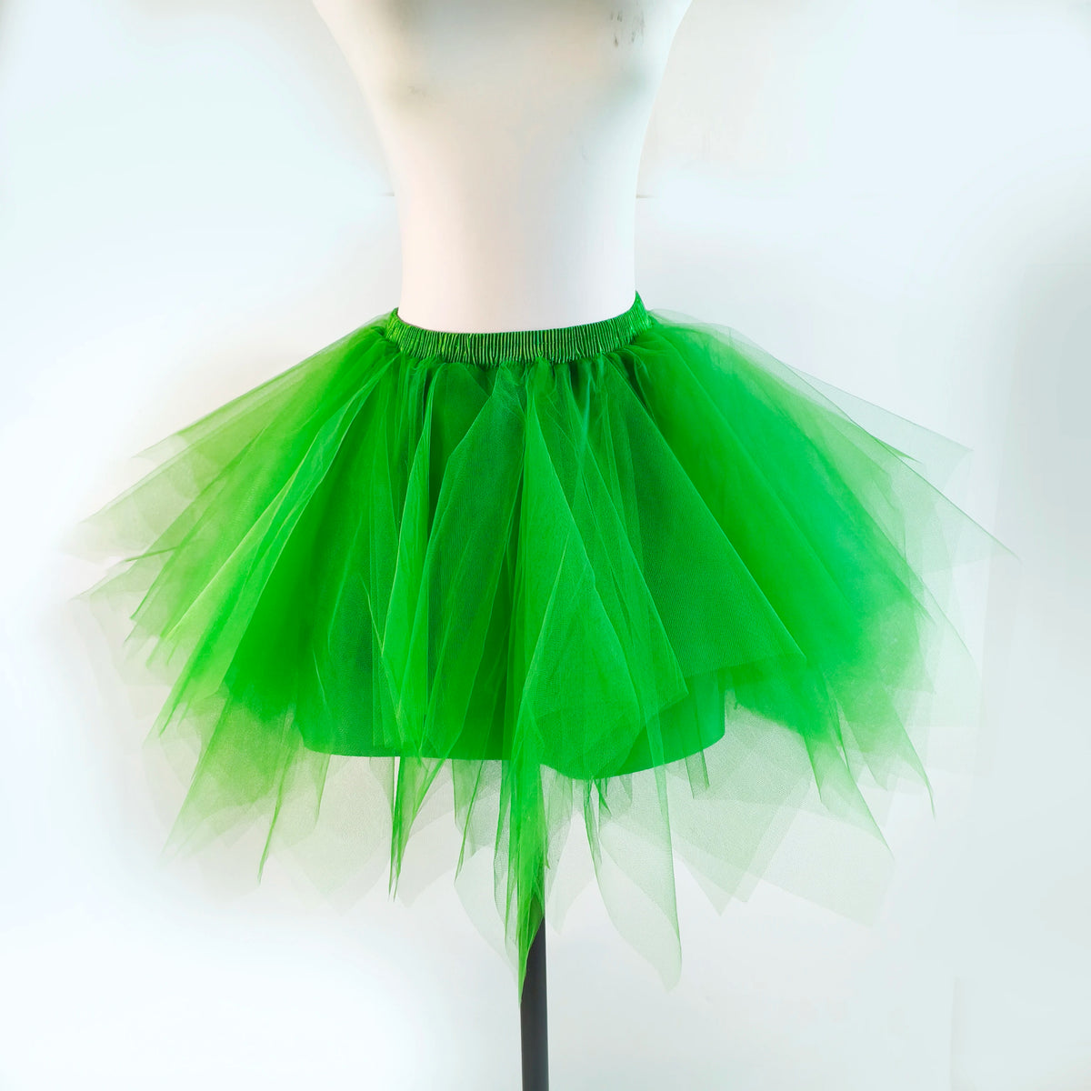 A bright green tulle tutu skirt displayed on a white mannequin.