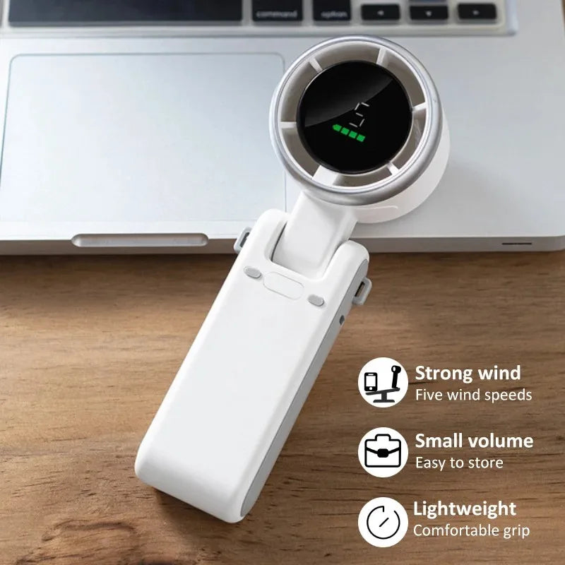 A white foldable mini handheld fan is shown resting on a wooden surface.