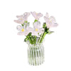 A bouquet of hand-blown glass flowers in pale pink and white arranged in a clear glass vase.