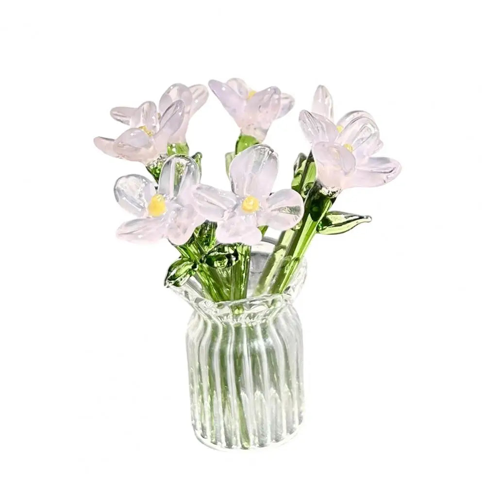 A bouquet of hand-blown glass flowers in pale pink and white arranged in a clear glass vase.