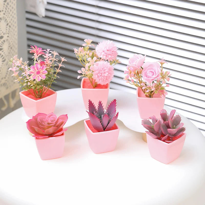 A set of six artificial potted plants in various shades of pink and purple displayed on a white surface.