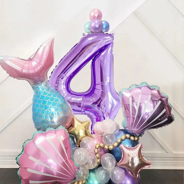 A set of iridescent and metallic purple balloons shaped like the number four and mermaid shells for a party decoration