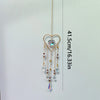 A gold-toned heart-shaped pendant featuring a clear crystal gemstone suspended by delicate chains.
