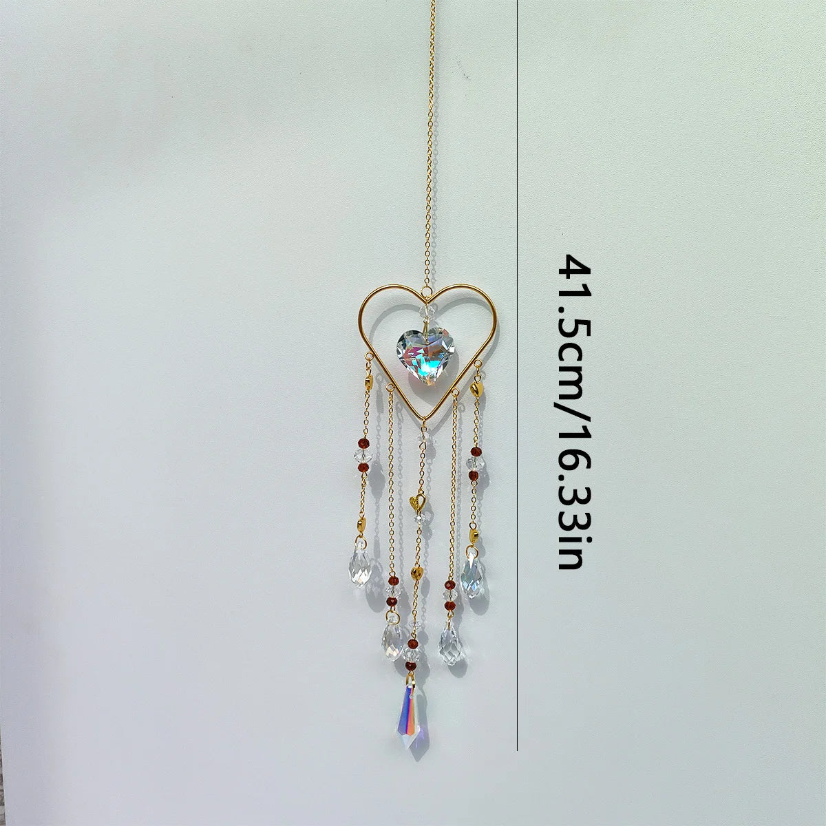 A gold-toned heart-shaped pendant featuring a clear crystal gemstone suspended by delicate chains.