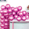 A collection of shiny pink and magenta metallic balloons piled on a white table.