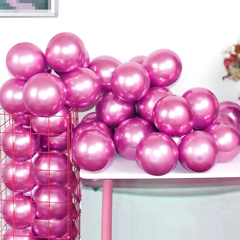 A collection of shiny pink and magenta metallic balloons piled on a white table.