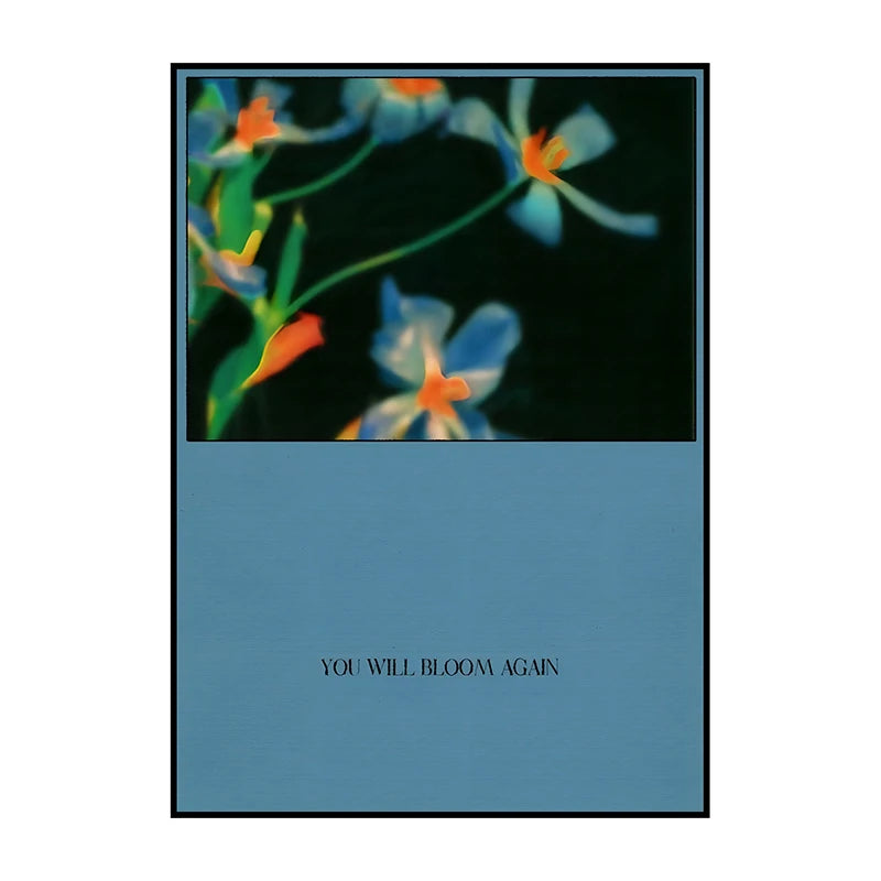 A framed painting featuring blue and orange flowers against a dark background with the text You Will Bloom Again.