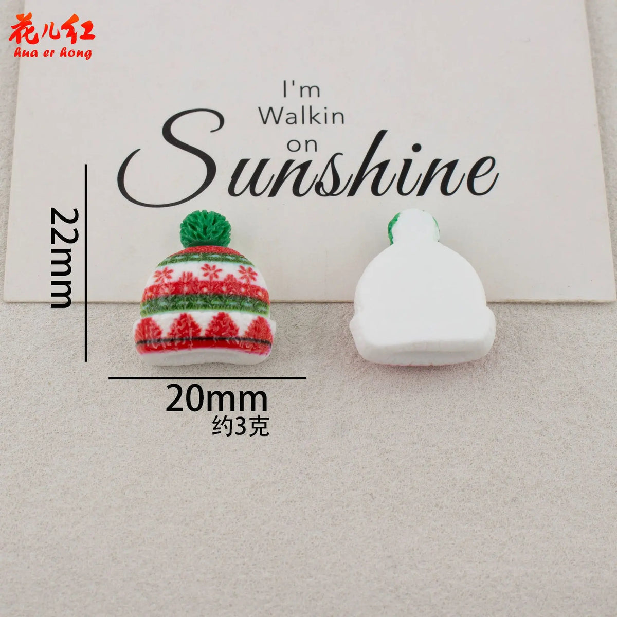 A white resin cabochon with red and green festive patterns and a green pom-pom, displayed on a light background.