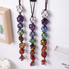 A set of natural crystal chakra rolling stone pendants hanging on a white wooden board.