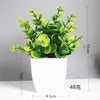 A potted artificial bonsai plant with bright green eucalyptus leaves in a white cylindrical pot.