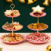 A three-tier pink dessert rack displaying various cookies and a star-shaped pastry on a wooden surface.