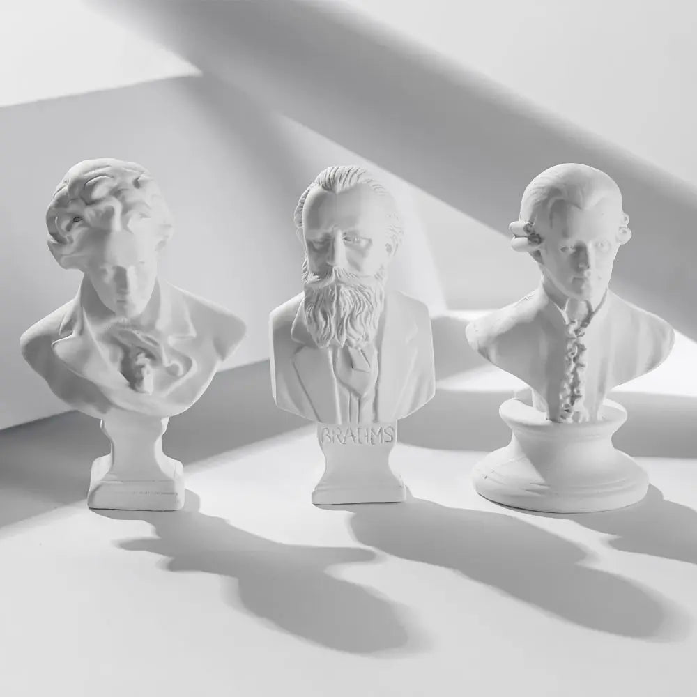 Three plaster bust miniatures of male figures with beards and hair, displayed in a studio setting.