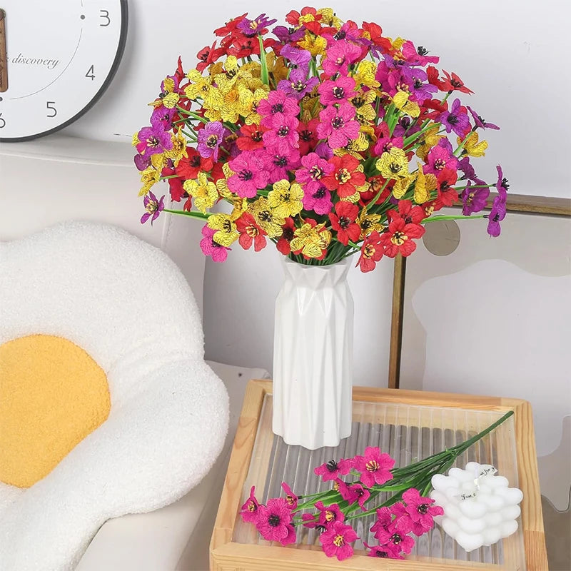 A vibrant bouquet of silk artificial flowers in shades of pink, yellow, and red arranged in a white vase on a wooden tray.