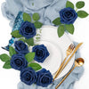 A bouquet of dark blue artificial foam roses and green leaves arranged on a white plate and light blue fabric.