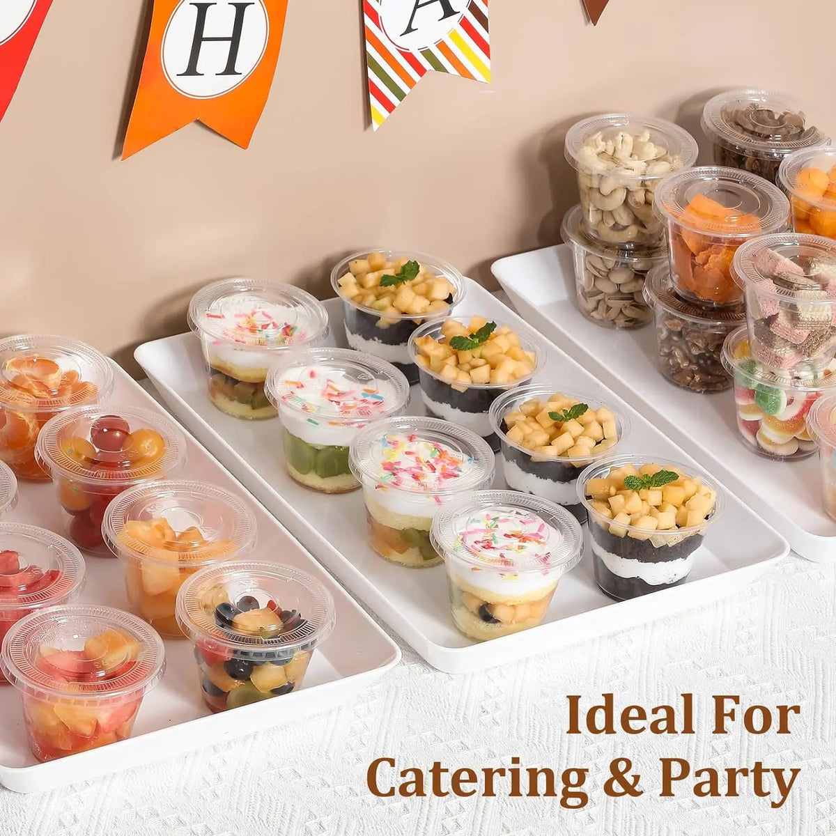 A platter of various savory snacks like nuts, dried fruit, and cheese, served in clear disposable plastic bowls for catering.
