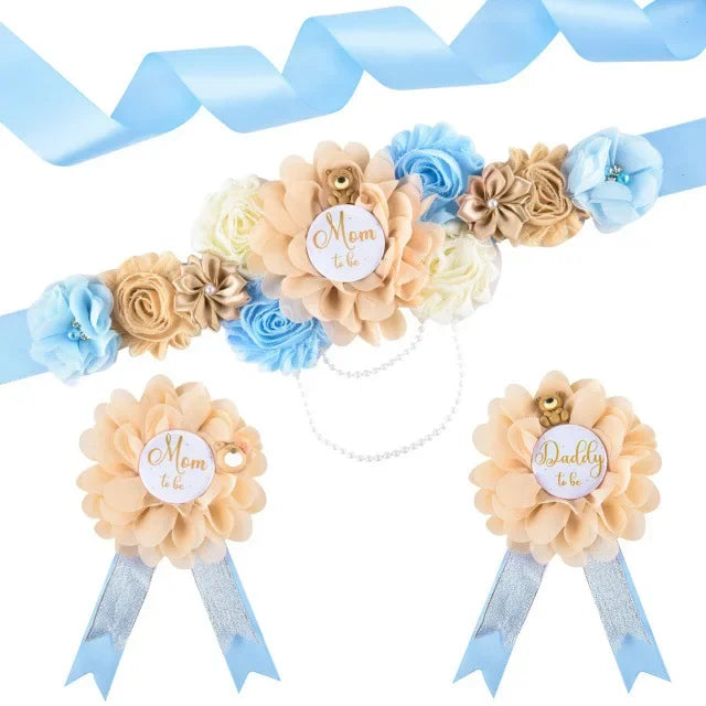 A set of peach and blue floral corsages and a light blue ribbon for a maternity sash