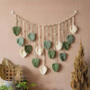Bohemian macrame leaf wall hanging featuring various green and cream leaves with dangling tassels.