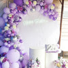 A colorful balloon arch featuring purple and pink latex balloons for a birthday celebration backdrop.