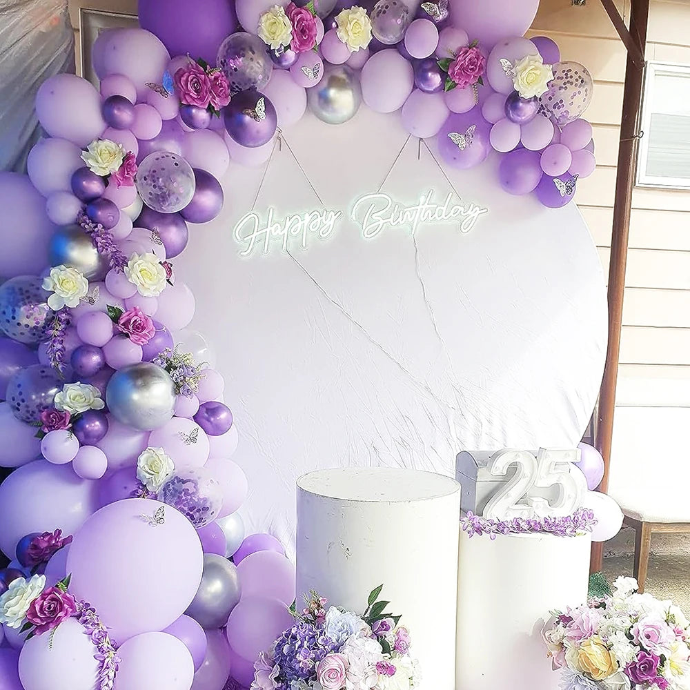 A colorful balloon arch featuring purple and pink latex balloons for a birthday celebration backdrop.