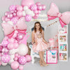 Pink and white balloon wreath archway set with pink balloons and a girl sitting in front