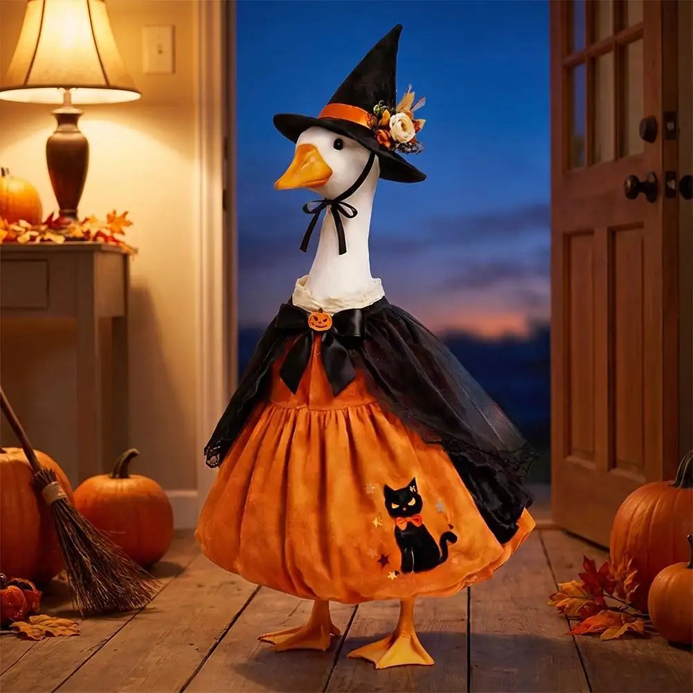 A decorative Halloween lawn goose costume featuring an orange body, black cape, and witch hat set against a twilight backgrou
