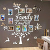 A wall decoration featuring a large tree silhouette made of white wood cutouts and framed family photos on a gray wall.