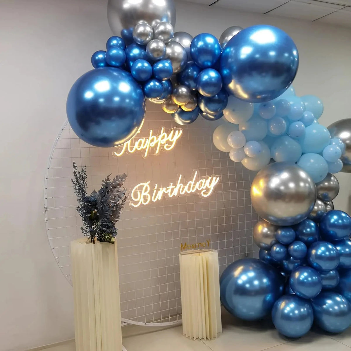 A balloon arch decoration featuring blue and silver balloons with a happy birthday sign.