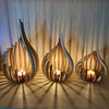 Handcrafted wooden lotus candle holder with a glowing flame set against a light wood background.