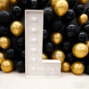 A large white marquee light-up letter is displayed against a background of gold and black balloons.