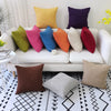 A collection of colorful linen pillows, including yellow, purple, green, pink, and orange, arranged on a white sofa.