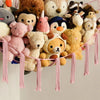 A collection of various stuffed animals and plush toys hanging from a pink fabric hammock.