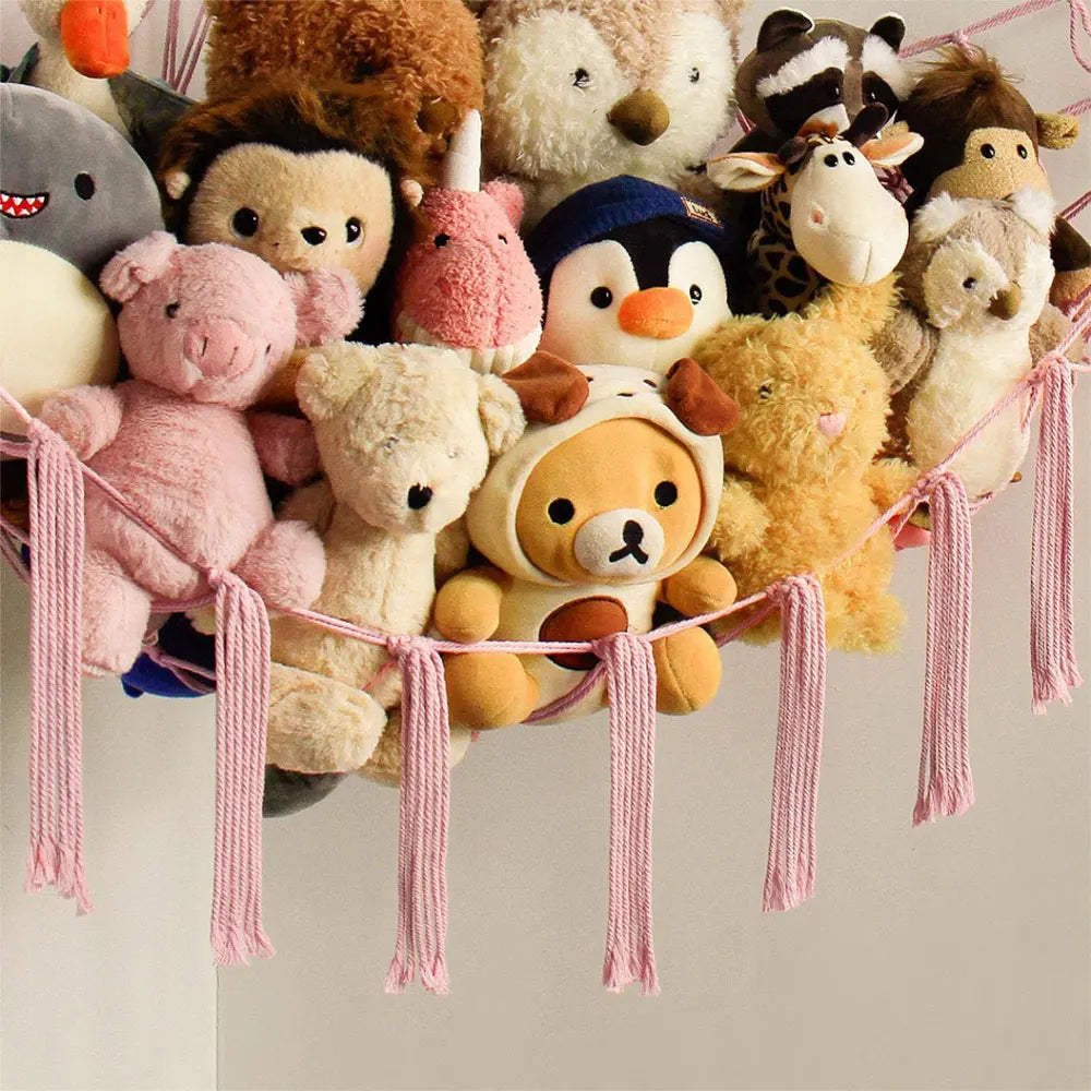 A collection of various stuffed animals and plush toys hanging from a pink fabric hammock.