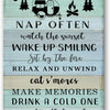 A rustic metal wall sign with text listing camping rules and activities like watching the sunset, sitting by the fire, and ma