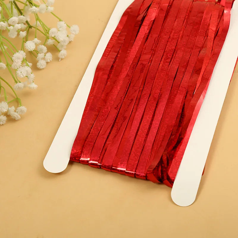 Red metallic tinsel foil fringe curtain backdrop for parties displayed on a light background.