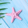 Pink starfish ocean animal cake topper set on a light blue wooden surface