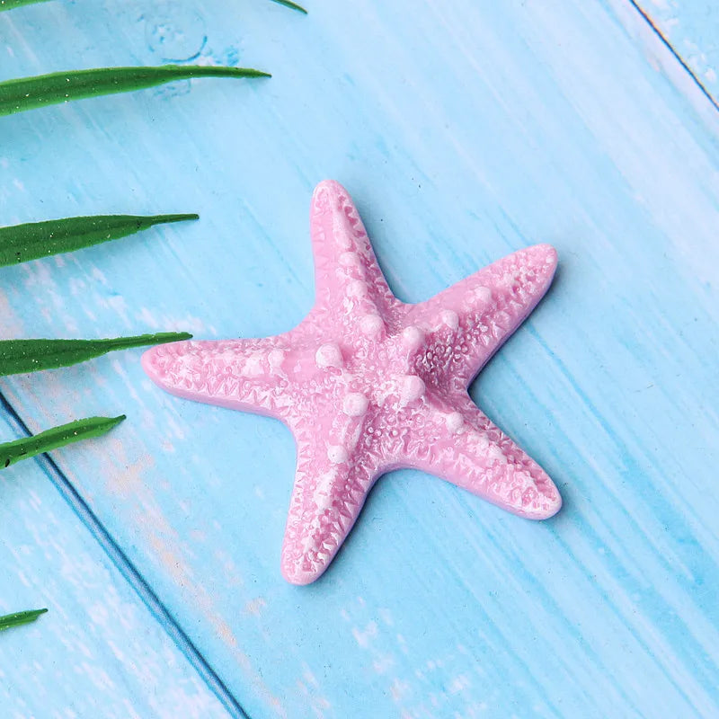 Pink starfish ocean animal cake topper set on a light blue wooden surface
